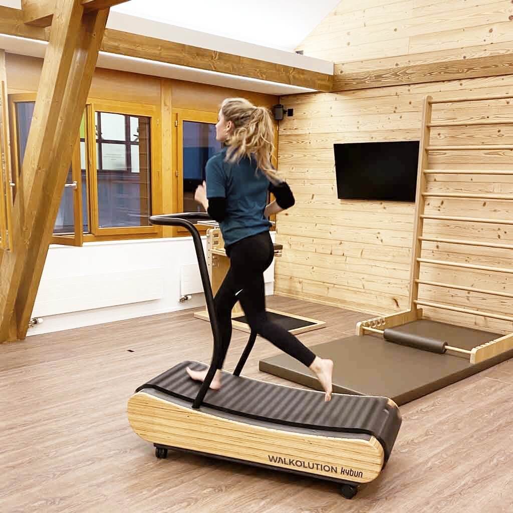 Young woman running on soft wooden treadmill, barefoot treadmill WALKOLUTION 